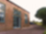 Front of Felldyke Bunkhouse. Brik building with large windows and a gravel parking area.